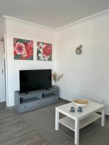 a living room with a flat screen tv and a table at Acogedor bungalow con vistas in Puerto de la Cruz