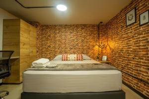 1 dormitorio con 1 cama en una pared de ladrillo en INDUSTRIAL LODGE, EN CALI, IMBANACO, Hospedaje Mi Fortaleza Cali en Cali