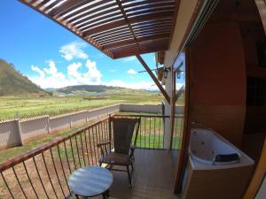 einen Balkon mit einer Badewanne, einem Tisch und einem Stuhl in der Unterkunft Alojamiento Exclusivo en el Valle Sagrado in Cusco