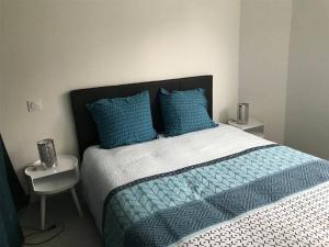 1 dormitorio con 1 cama grande con almohadas azules en Appartement avec jardin privatif en Lorient