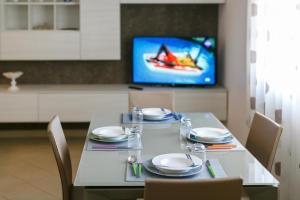a dining room table with chairs and a tv at LA CONCHIGLIA SAMS HOME in Bisceglie
