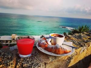 a cup of coffee and croissants on a rock with the ocean at Mediterranean Boutique Hotel in Tropea