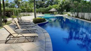 a row of lounge chairs next to a swimming pool at Flat Barra da Tijuca - Gastão Sengés in Rio de Janeiro