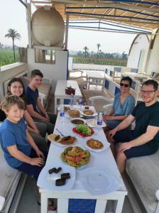 un grupo de personas sentadas alrededor de una mesa con comida en Moon Valley Apartments, en Luxor