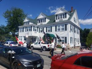 a group of people holding flags in front of a house at Little Fig Hotel in Bar Harbor