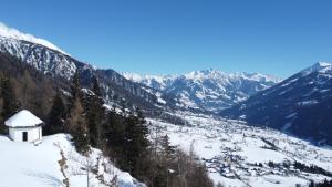 eine schneebedeckte Bergkette mit einem kleinen weißen Gebäude in der Unterkunft Budamerhof in Virgen