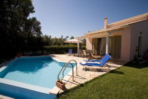 a swimming pool with two chairs and a house at Villa Fotini in Lefkada Town