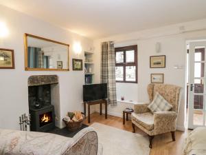 a living room with a fireplace and a tv at Daffodil Cottage in Grange Over Sands
