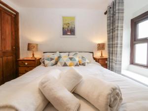 a bedroom with a bed with white sheets and pillows at Daffodil Cottage in Grange Over Sands