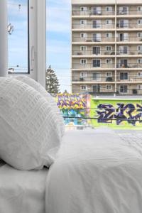 a bed with a white pillow in front of a window at Chic 1BR Kensington unit W/Parking in Calgary