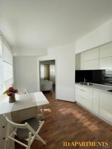 een keuken met witte kasten en een tafel en stoelen bij ID Apartment in Vir