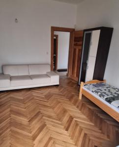 a living room with a white couch and wooden floors at Ubytovanie Topoľčany in Topoľčany