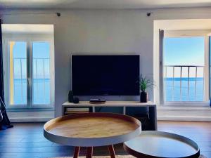 a living room with a flat screen tv and two tables at Appartement Casaluna - Casadibastia - Vue mer Citadelle in Bastia