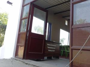 una puerta abierta de una casa con sillas verdes en OYO 81031 Golden Hotel And Restaurant, en Muzaffarnagar