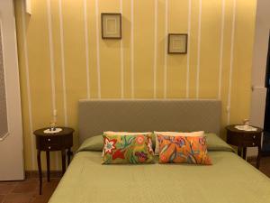 uma cama com duas almofadas num quarto com duas mesas em Casetta Lele Locazione breve em Siracusa