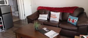 a living room with a brown leather couch with pillows at WineDownHere - Lic. 75806 in Kelowna