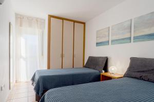 um quarto com 2 camas e uma janela em Apartamentos Turisticos CAN CUNILL em Es Pujols