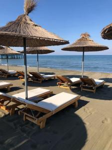 un grupo de sillas y sombrillas en una playa en Beni Rooms Tale, en Lezhë