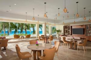 un vestíbulo con mesas, sillas y TV en Dreams Sands Cancun Resort & Spa, en Cancún