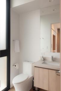 a white bathroom with a toilet and a sink at Residencias Cityzen cerca del Aeropuerto in Echeverría