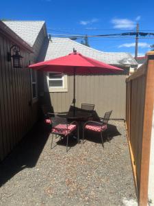 a patio with a table and two chairs under a red umbrella at NEW! Unique Coeur d’Alene Cottage. 1/2 Mi to Dtwn in Coeur d'Alene