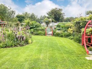 um jardim com um relvado verde e uma cerca vermelha em Spa Cabin em New Milton