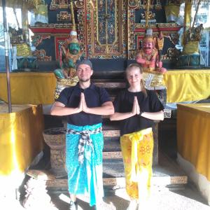 Um homem e uma mulher a fazer ioga em frente a um templo. em Krisna Homestay em Pemuteran