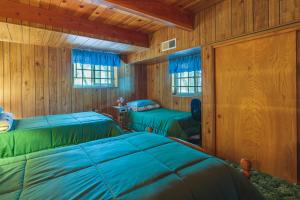two beds in a room with wooden walls at California Retreat Near Yosemite National Park! in Twain Harte