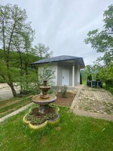 a small house with a fountain in the grass at Golden Dream in Jajce