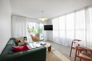 a living room with a green couch and a table at Blush on Broadbeach- beachside and pet friendly in Gold Coast
