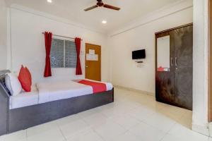 a bedroom with a bed with red curtains and a tv at Hotel O Sai Residency in Pune