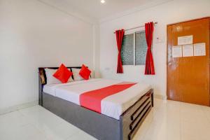 a bedroom with a bed with red pillows and a window at Hotel O Sai Residency in Pune