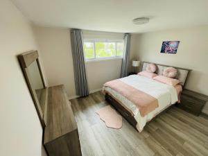um quarto com uma cama com almofadas cor-de-rosa e uma janela em Luxurious Cozy House in Bluffs with Lake View em Toronto