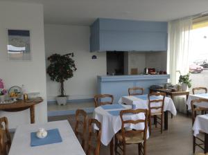 a restaurant with tables and chairs and a kitchen at Hotel Du Parc in Cabourg