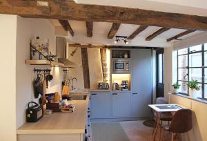 una cocina con armarios azules y una mesa. en Blacksmith's Cottage Suffolk en Lavenham