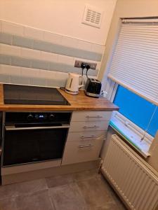 a kitchen with a counter top with a stove and a window at Two bedroom maisonette close toWarwick Uni in Canley