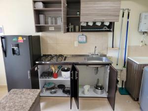 una pequeña cocina con fregadero y nevera. en APARTAESTUDIO en el Norte de Armenia, en la via a Salento y Filandia Con parqueadero de carro en Armenia