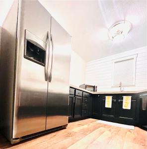 a kitchen with a stainless steel refrigerator and black cabinets at Farm Charm 