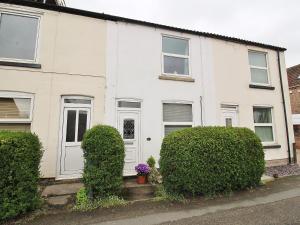 a white house with bushes in front of it at Bluebell Cottage in Selby