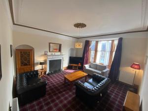 a living room with leather furniture and a fireplace at 92 High Street in Aberlour