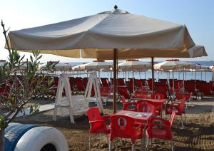 a group of tables and chairs under an umbrella on the beach at Savona Casa Vacanze vicino Mare 3 minuti WIFI in Savona