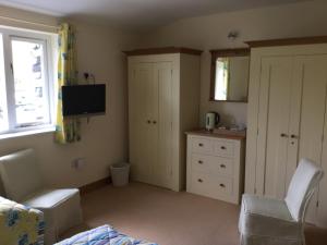 a bedroom with a bed and a chair and a tv at Bryn Derw in Talsarnau
