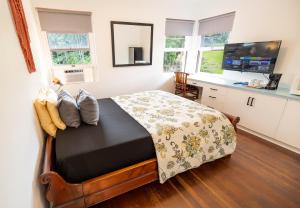 Hilltop Legacy Vacation Rental في هيلو: غرفة نوم بسرير ومكتب مع تلفزيون