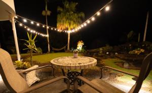 una mesa de patio y sillas en un patio con luces en Hilltop Legacy Vacation Rental, en Hilo