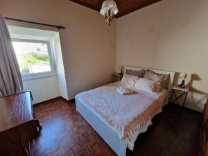 um quarto com uma cama branca e uma janela em Apartamentos Garrett em Horta