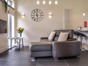 a living room with a couch and a clock on the wall at Viola Cottage in Blairgowrie