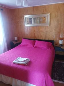 a pink bed with a towel on top of it at Cabaña ANN in Curiñanco