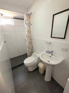 a white bathroom with a toilet and a sink at Fiflos Apartament in Cusco