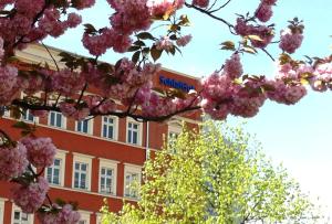 un bâtiment avec des fleurs roses devant un bâtiment dans l'établissement SchlafGut AppartementHotel, à Leipzig