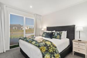 a bedroom with a large bed and a large window at Nga Roto Retreat - Taupo in Taupo